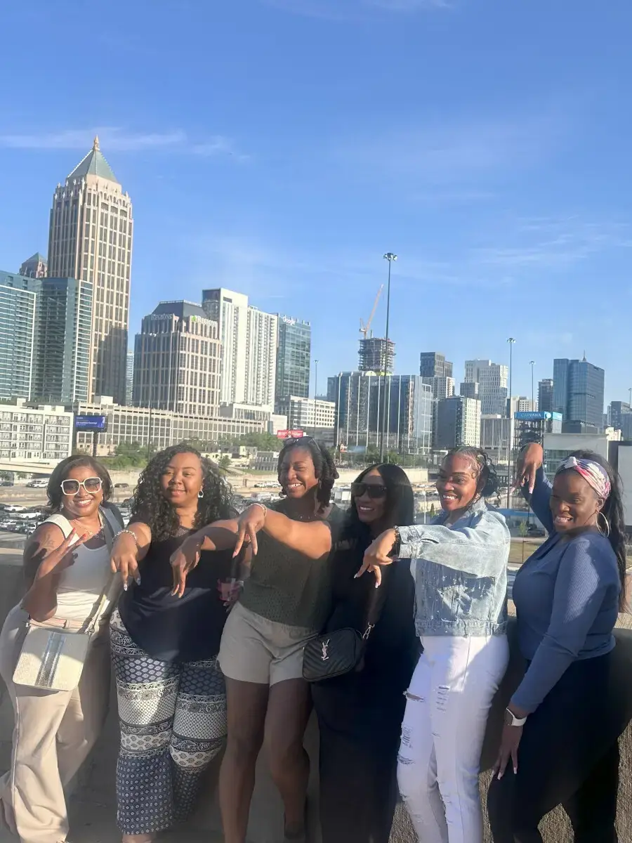 Friends posing with the Atlanta skyline behind them